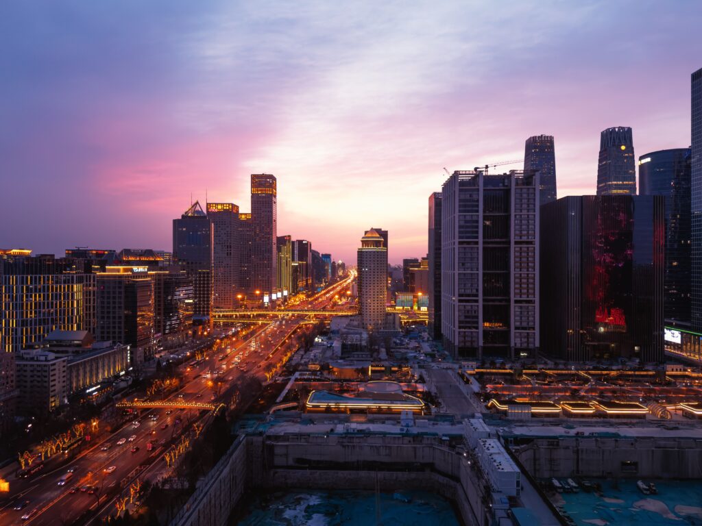 A breathtaking panoramic view of Beijing's urban skyline at dusk with vibrant city lights and a colorful sky.