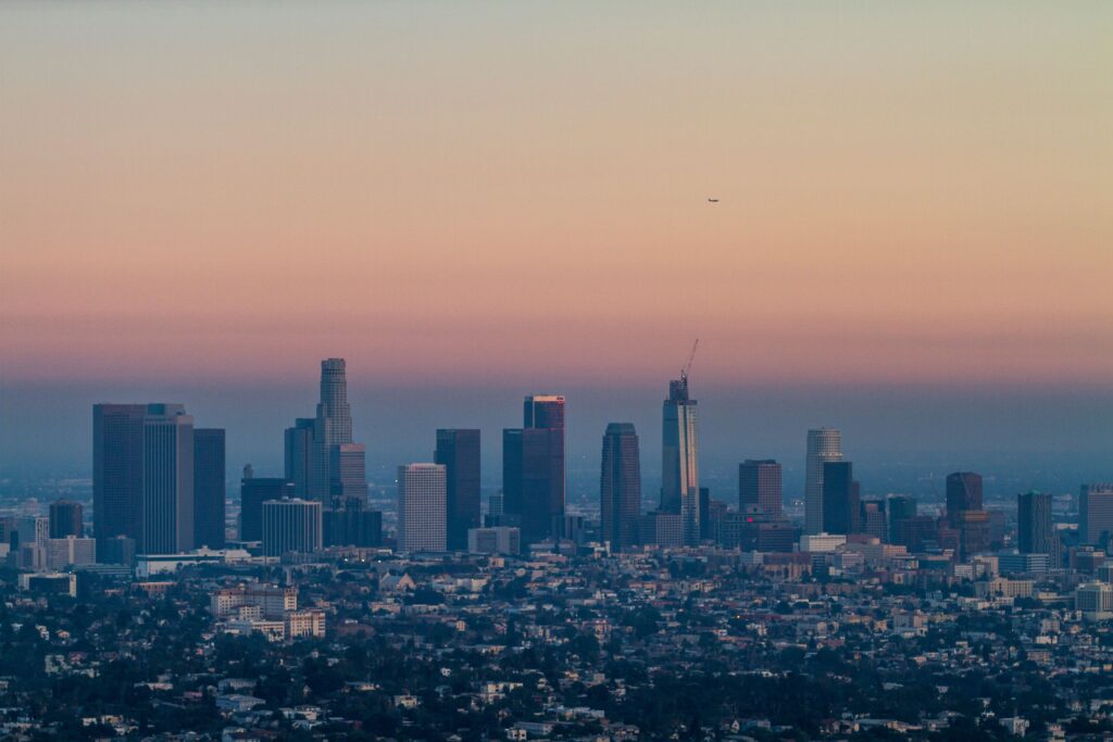 Stunning view of Los Angeles skyline with vibrant sunset hues, highlighting iconic skyscrapers and urban landscape.